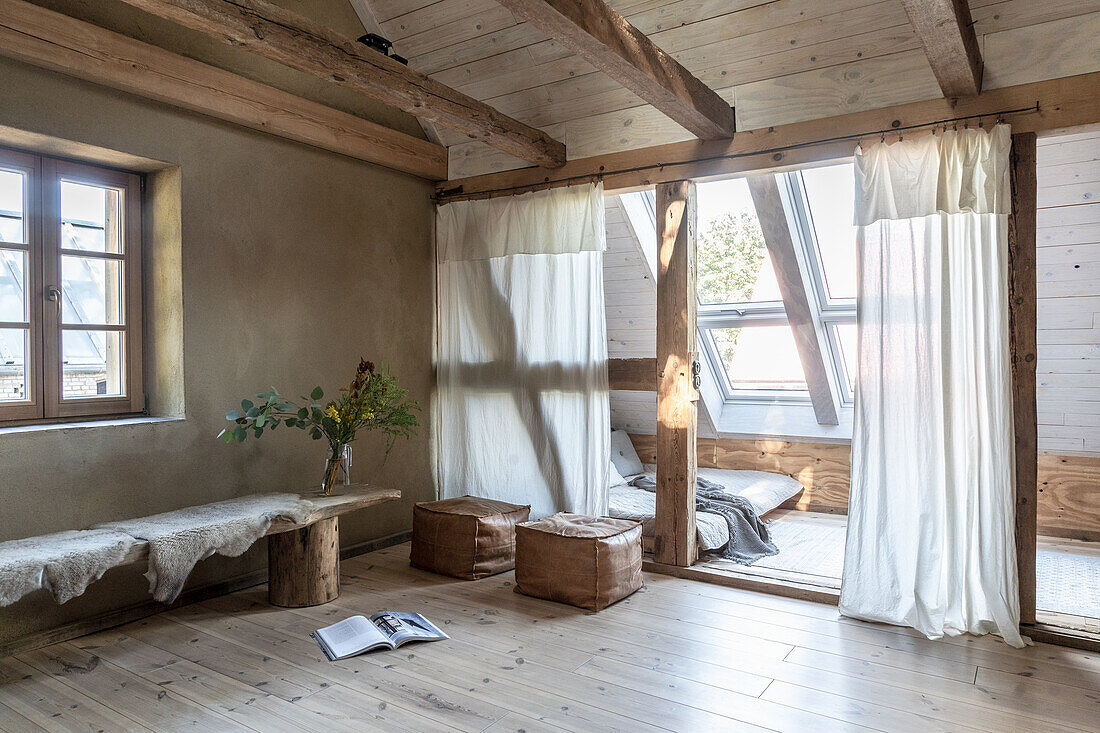 Holzbank mit Schaffell als Tisch und Lederwürfel, Schlafbereich mit Dachschräge in altem Landhaus
