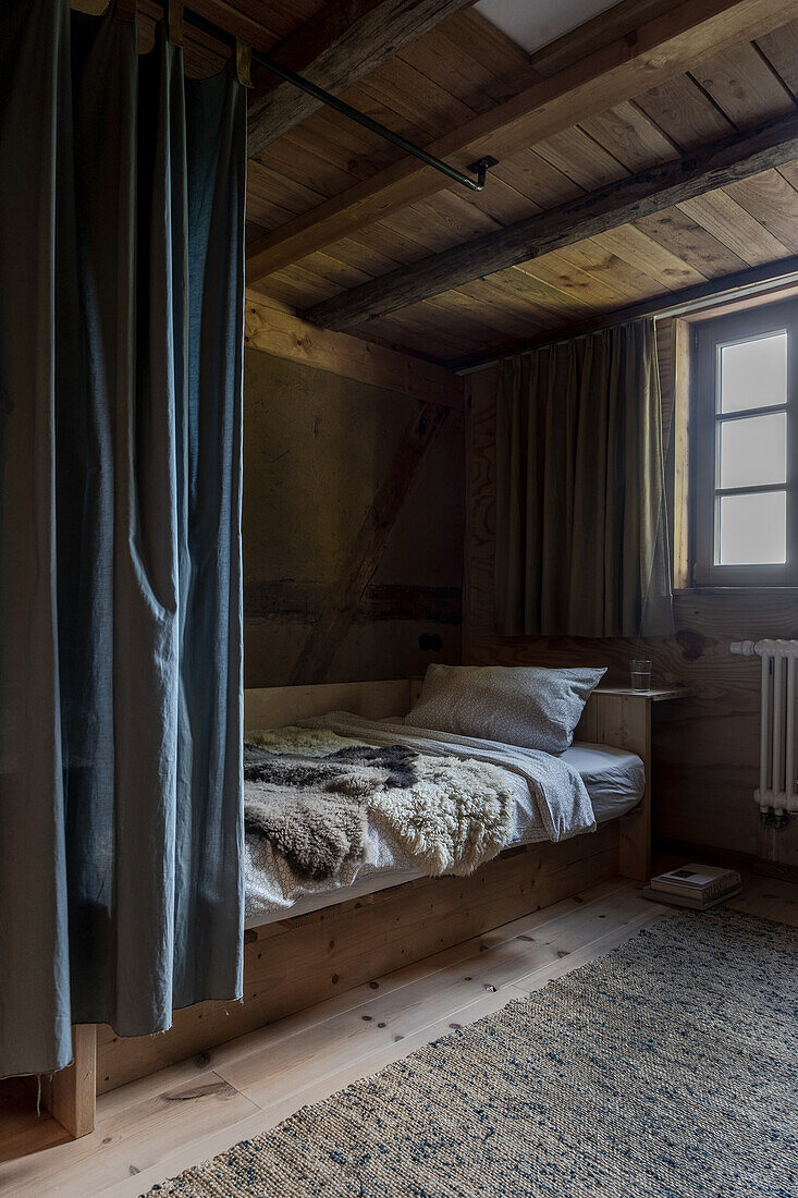 Einzelbett mit Vorhang im Zimmer mit recycelter Holzdecke