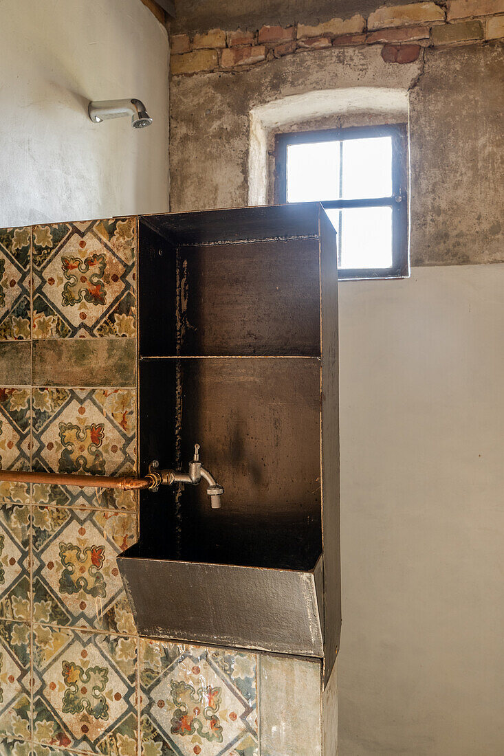 Sink from old metal cupboard against wall with ornamental tiles