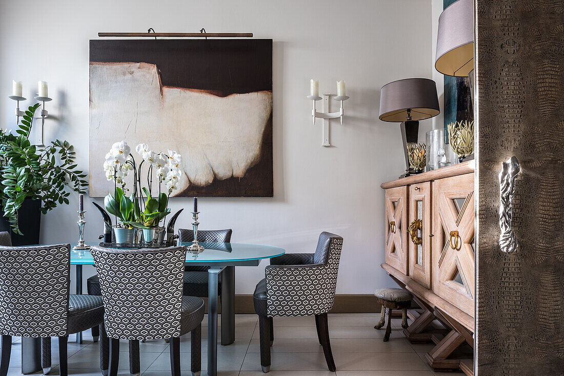 Ovaler Tisch mit gepolsterten Stühlen, moderne Kunst und großes Sideboard aus Holz im Esszimmer