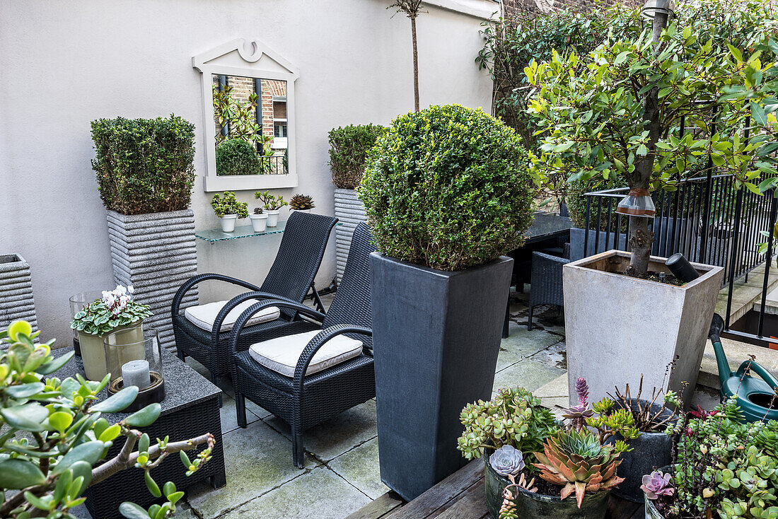 Elegante Terrasse in Grautönen mit Outdoormöbeln und Pflanzkasten