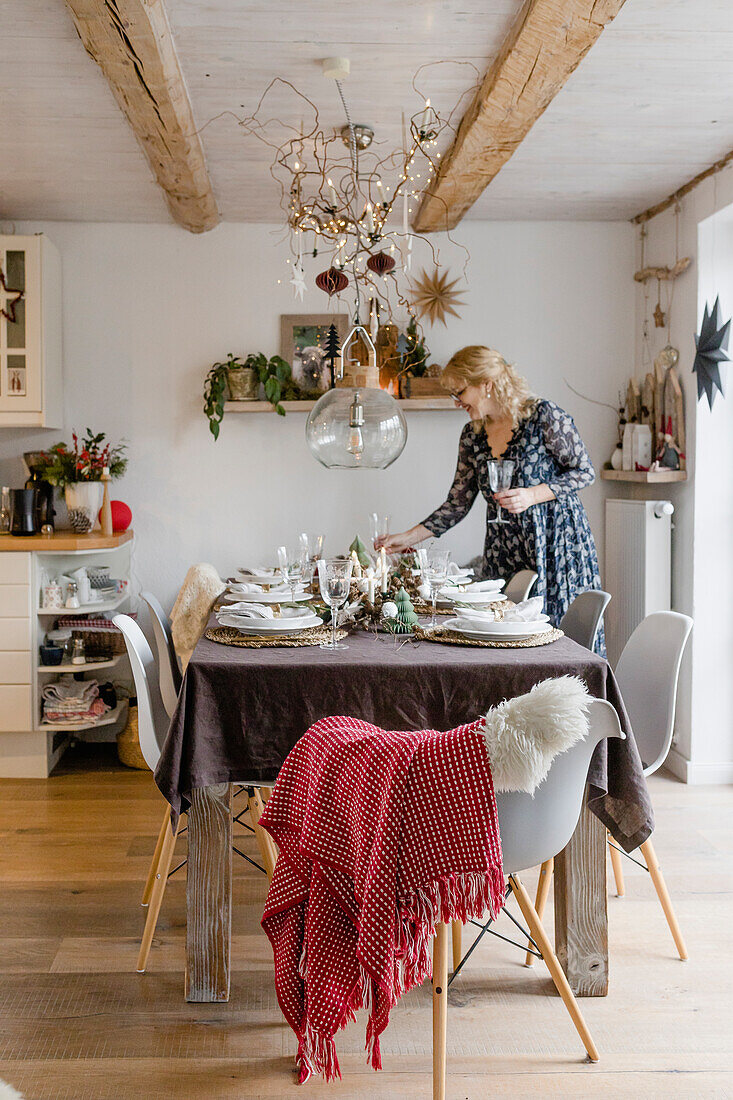 Woman setting the table in Christmas decorated dining area