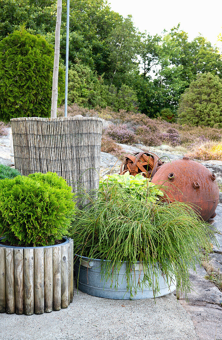 Planters, behind them rusted garden decorations in a rock garden