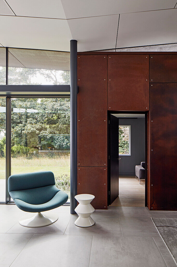 Designermöbel - Sessel und Beistelltisch vor Wand aus Cortenstahl mit Tür