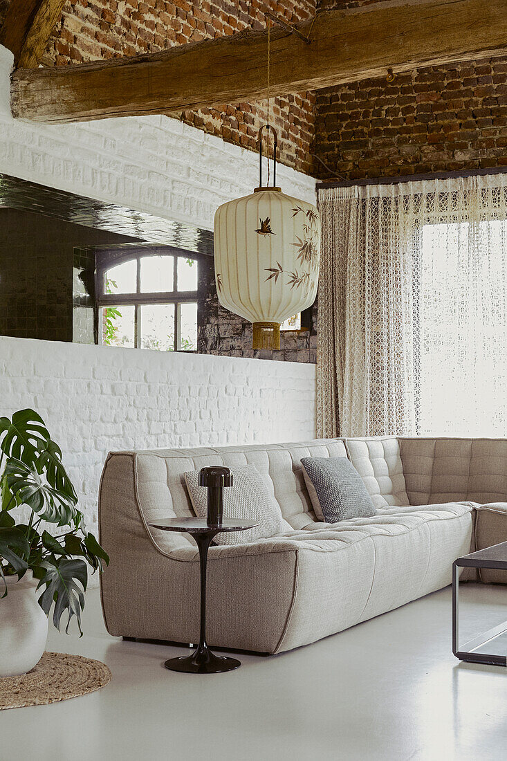 Modulare Sofa in Beige im Zimmer mit weiß getünchter Ziegelwand