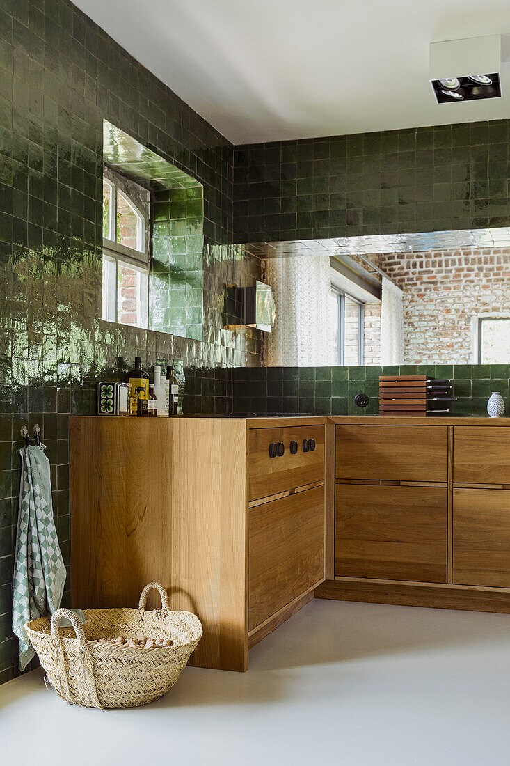 Wooden base cabinets in a kitchen with green wall tiles