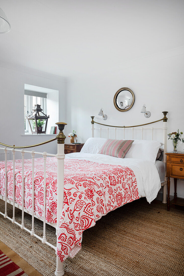 Double bed with red and white bedspread, lantern on windowsill