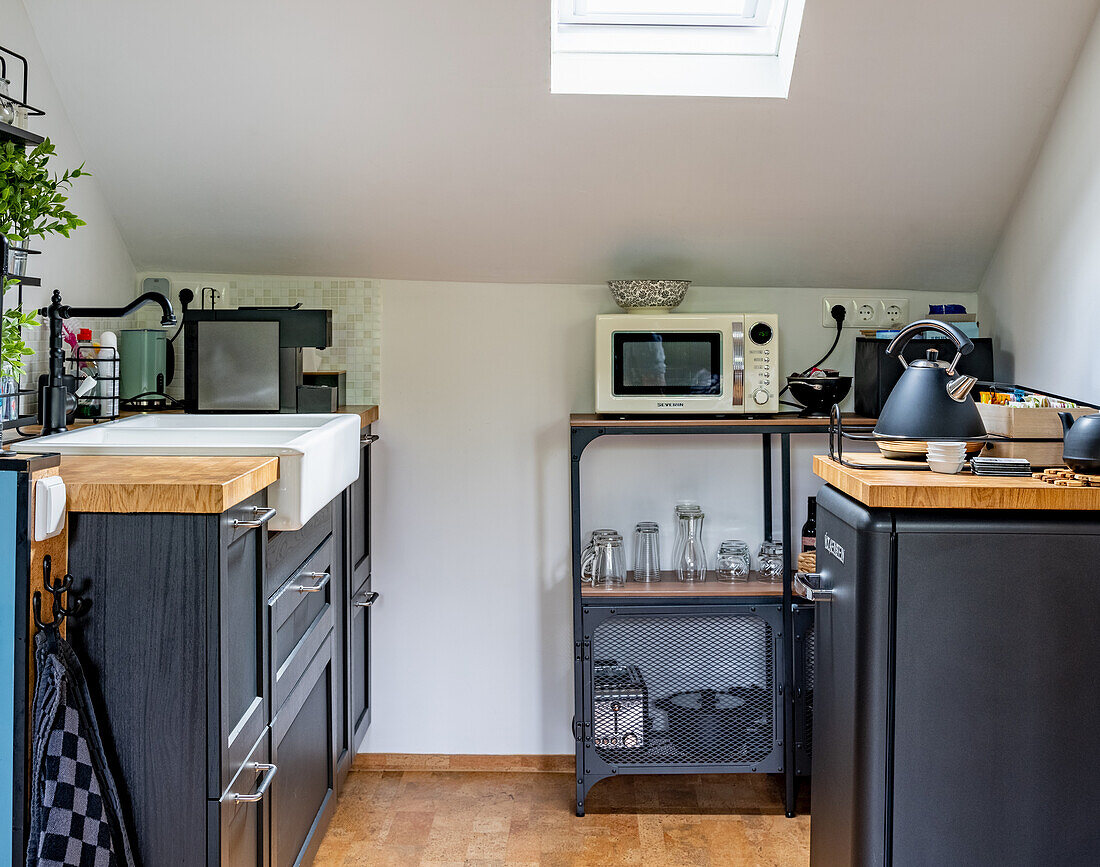 Small kitchen with grey cabinet fronts and open shelving in the attic
