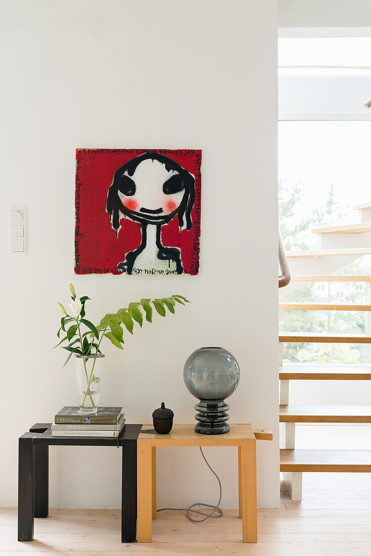 Two stools, painting hung above it next to the staircase
