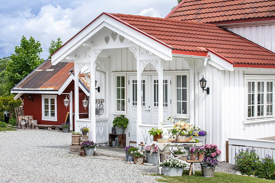 Weiß gestrichenes, skandinavisches Haus, davor Blumenarrangement