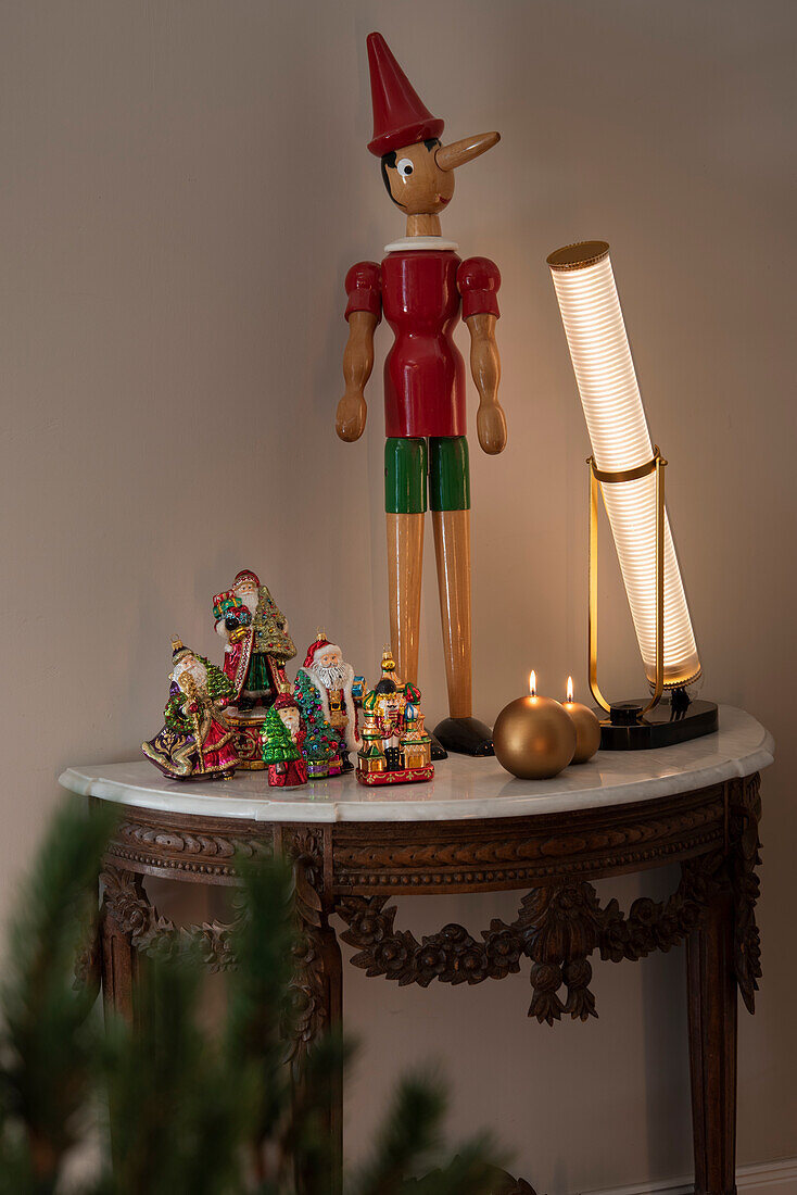 Console with Christmas decoration, wooden figure, and designer lamp