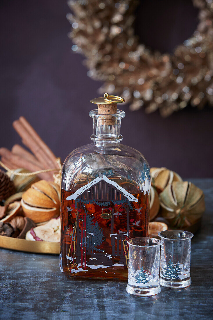 Christmas liqueur in decorative bottle in front of tray of potpourri
