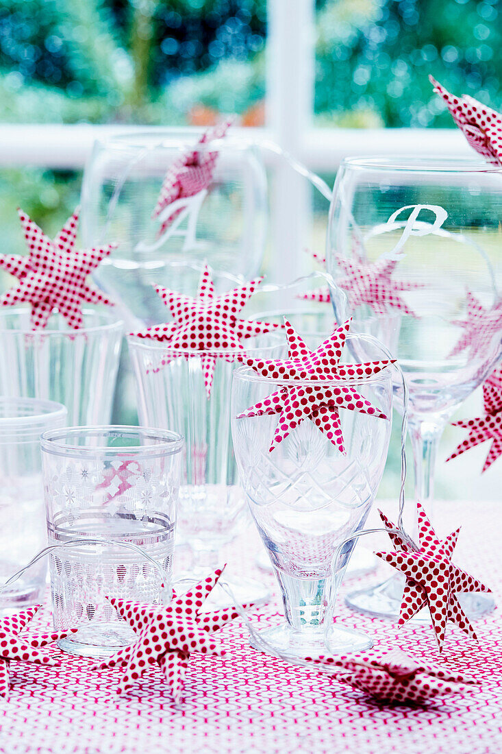 Gläser mit rot-weißer, sternförmiger Lichterkette auf Tisch