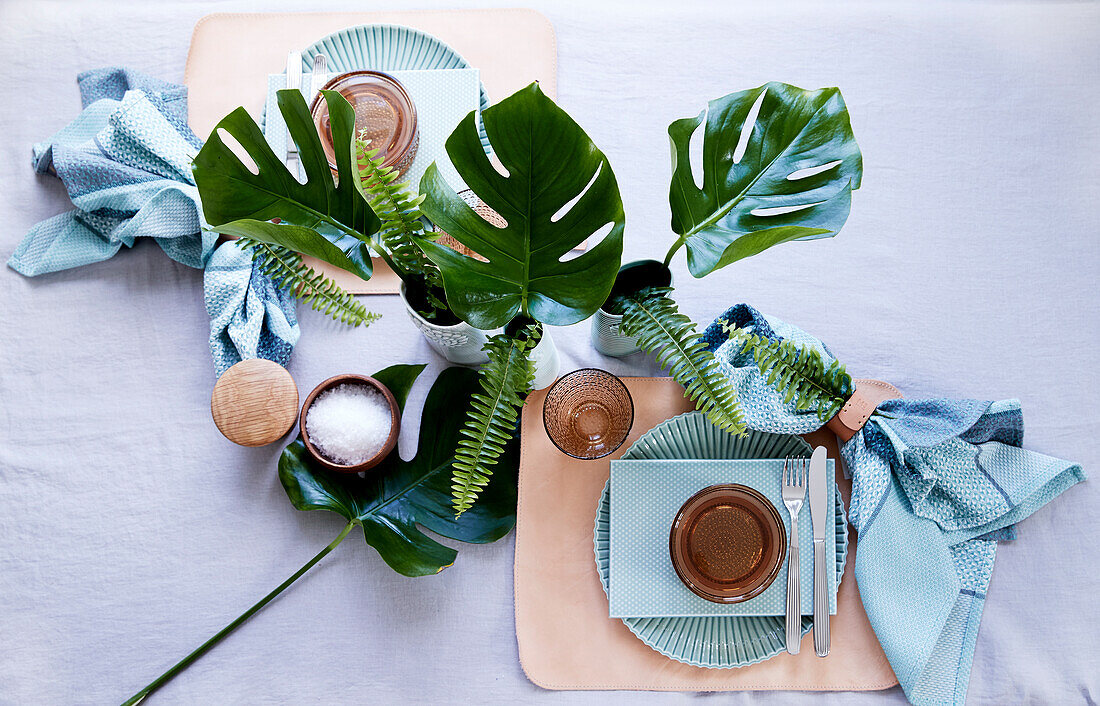 Table for two decorated with monstera and fern leaves