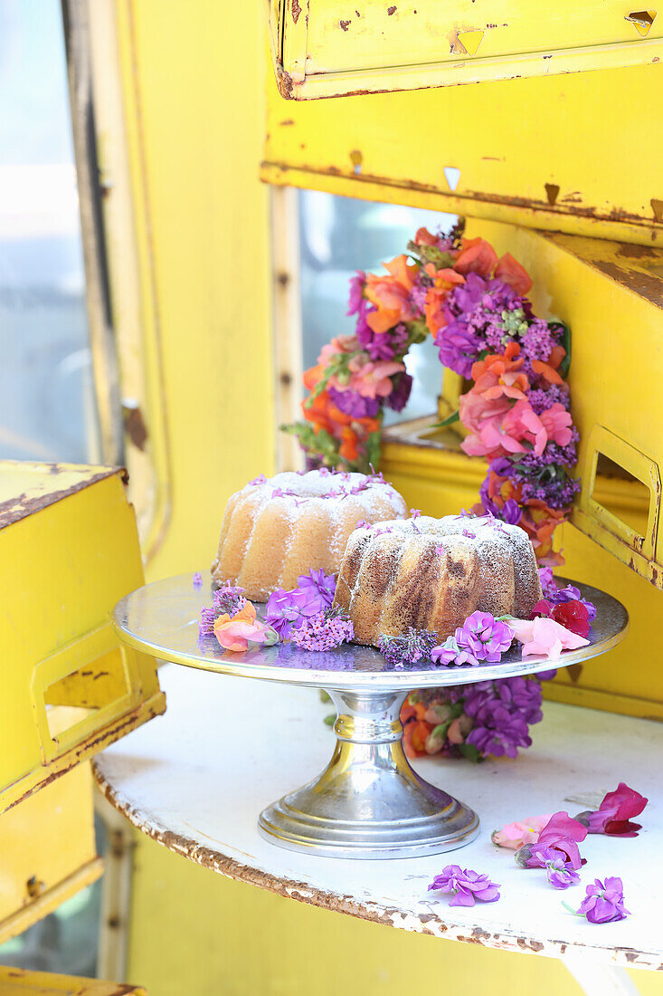 Bundt cakes on a metal stand, behind it a colorful wreath in a discarded gondola