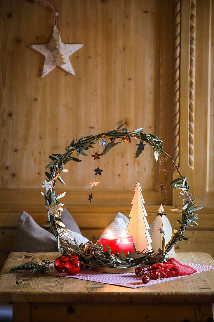 Christmas decorative wreath with candles and tree decor on a wooden table