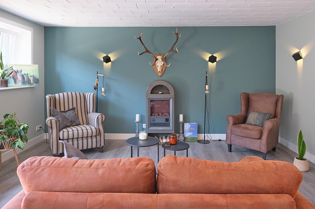 Upholstered furniture, side tables, a fireplace, antlers and wall lights in a living room