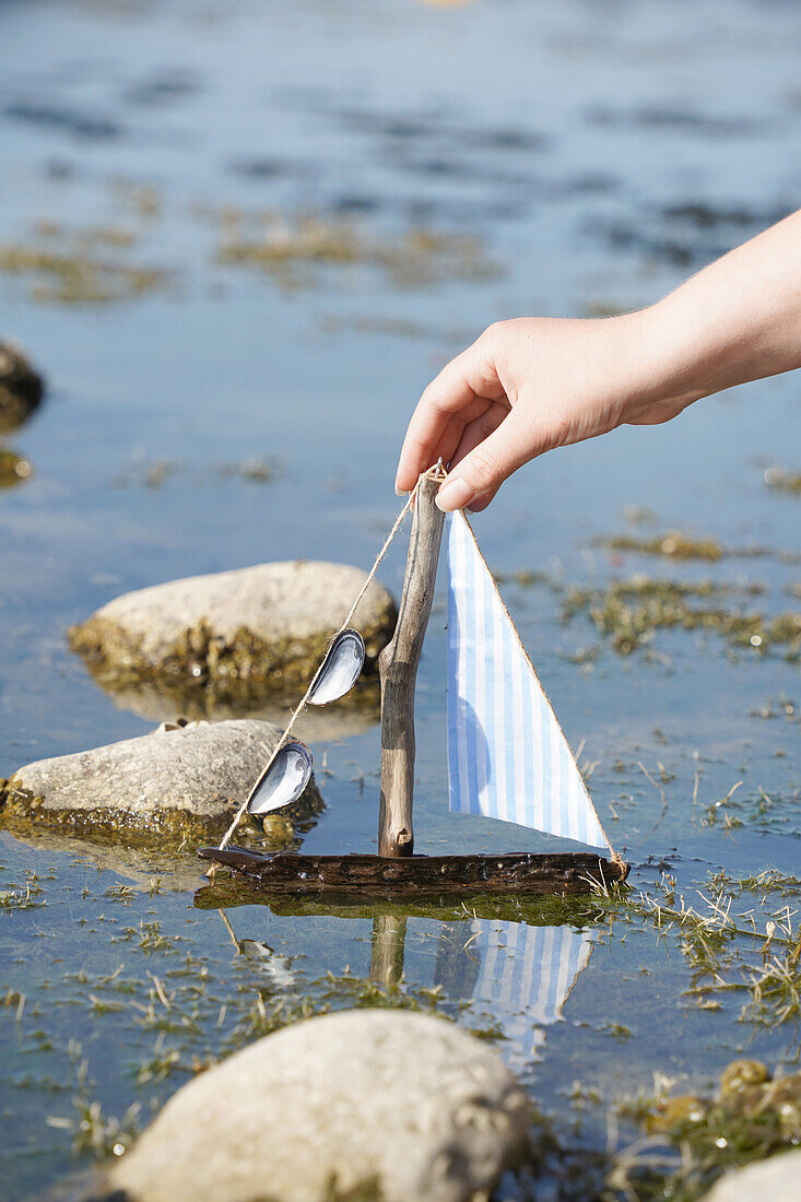 Handmade sailing boat made of driftwood and fabric in the water