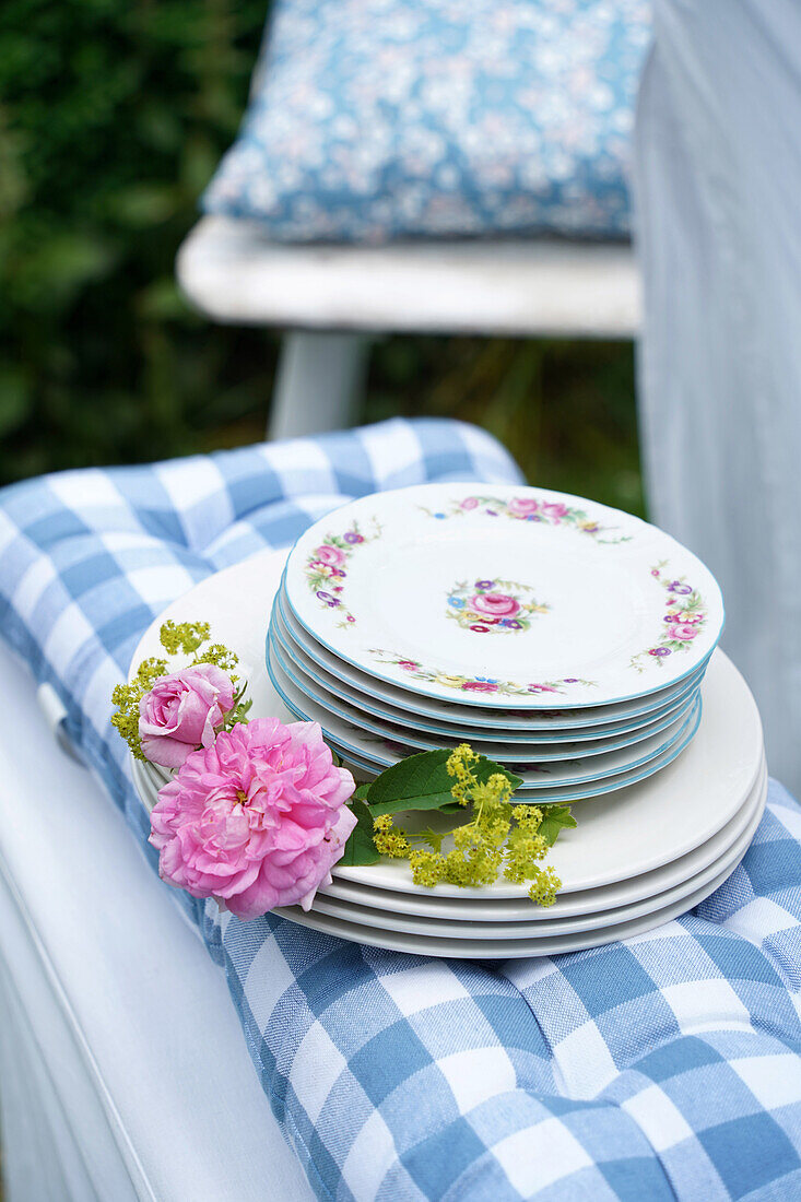 Stack of plates and floral decoration on a checkered seat cushion