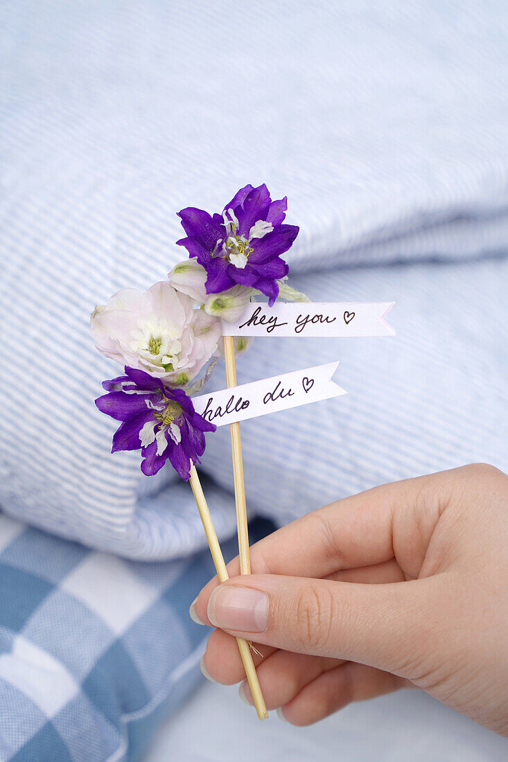 Two purple flowers with small greeting tags on blue and white fabric