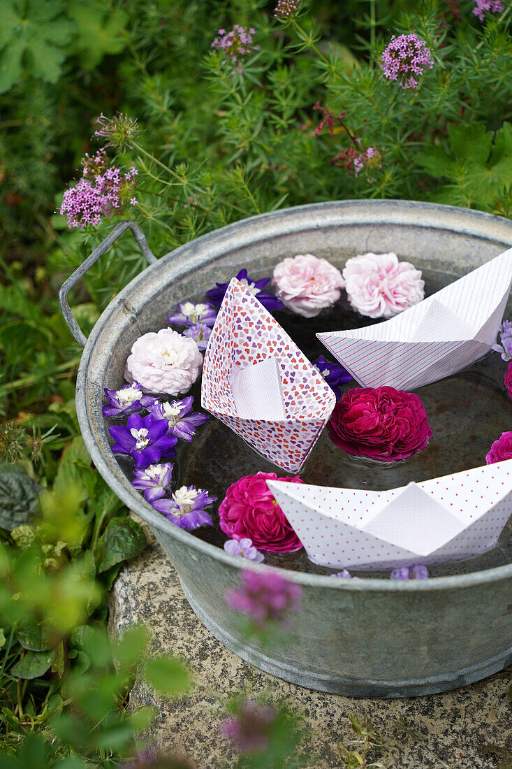 Paper boats and flowers in a zinc tub in the garden