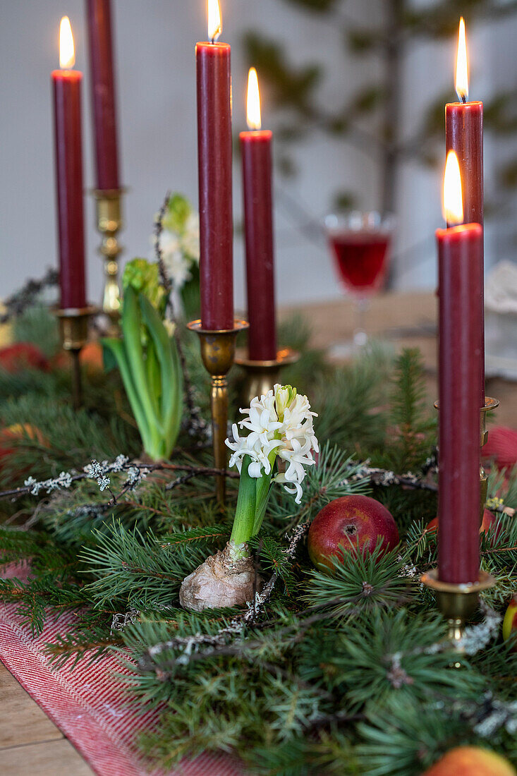 Weihnachtlicher Tischschmuck mit roten Kerzen, Hyazinthen und Tannenzweigen