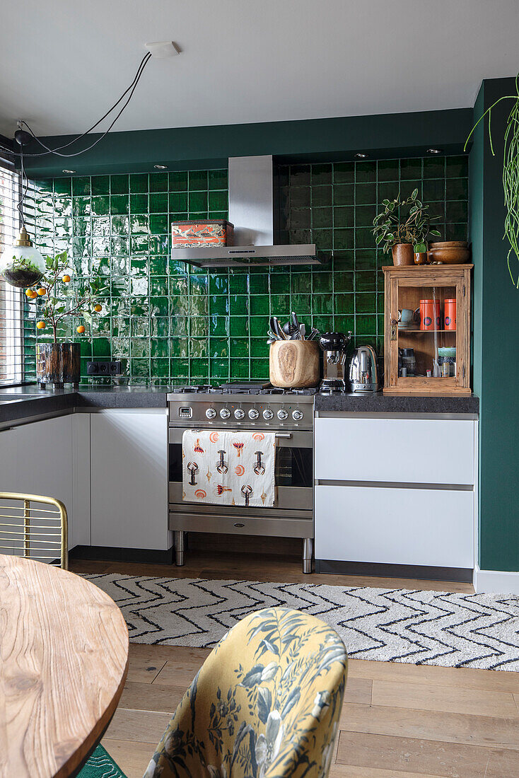 Modern kitchen with dark green tiled backsplash and stainless steel gas oven