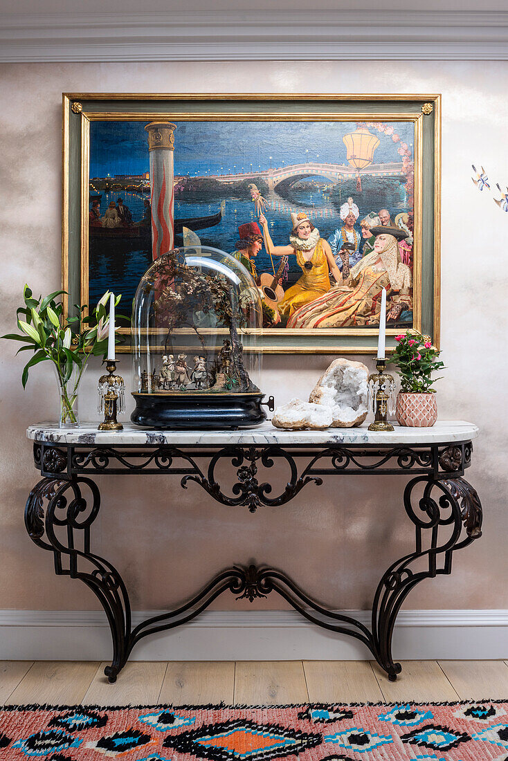 Ornamented French console with phalibois under glass bell jar, flanked by paintings