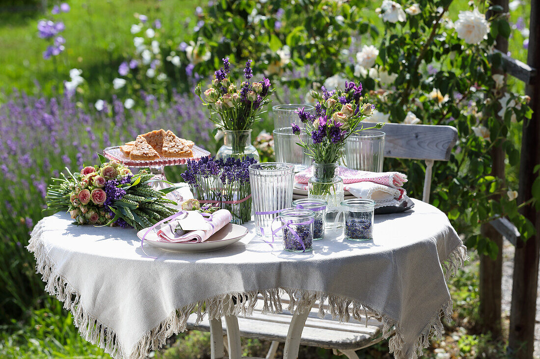 Gedeckter Gartentisch mit Lavendel und Blumensträußen im Sommergarten