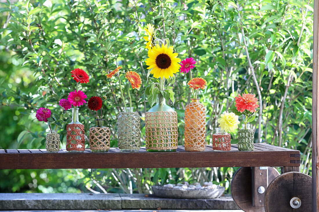 Colourful summer flowers in macramé vases on garden bench