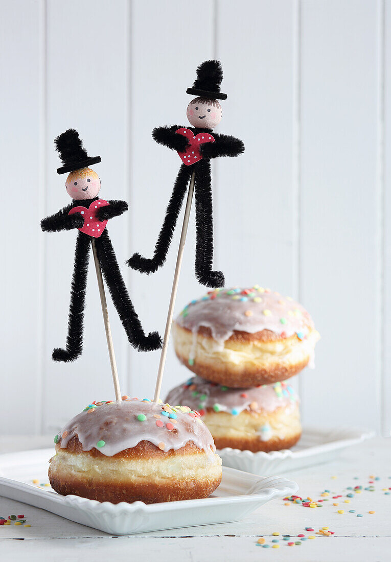 Pipe cleaner men holding hearts stuck in doughnuts
