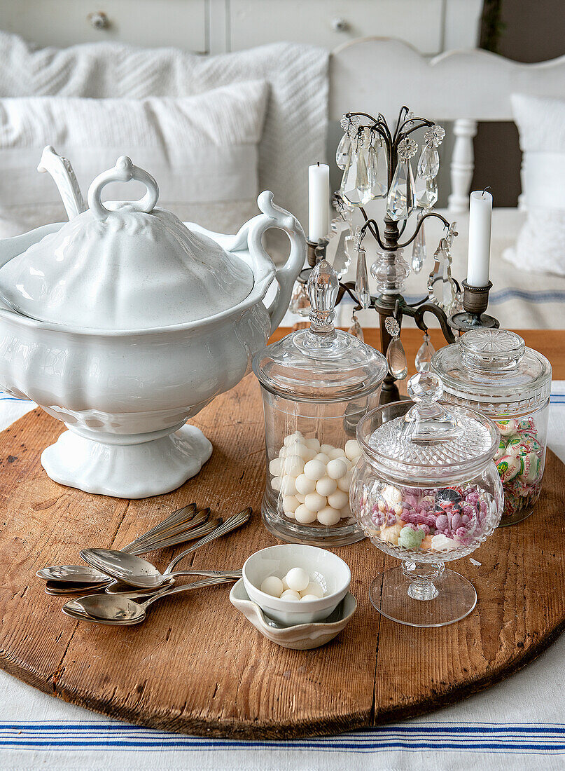 Round wooden table with antique porcelain soup tureen and glass jars full of sweets