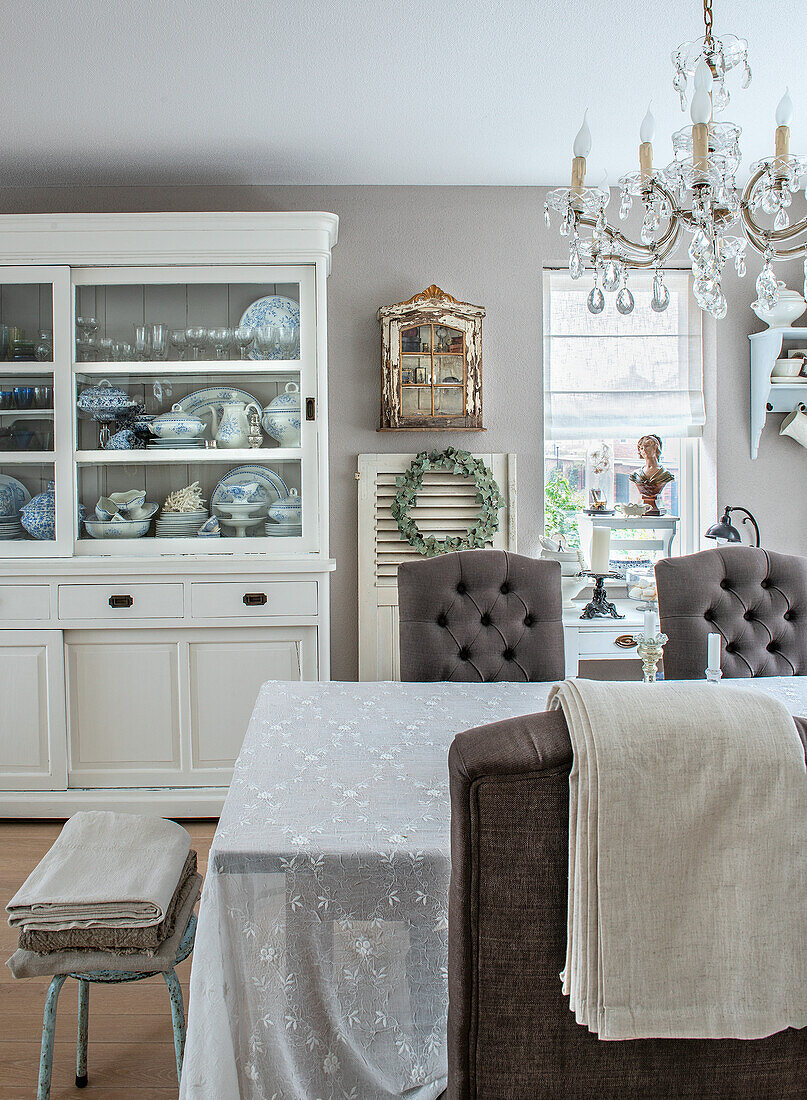 Dining room with white display cabinet and chandelier, table with embroidered tablecloth