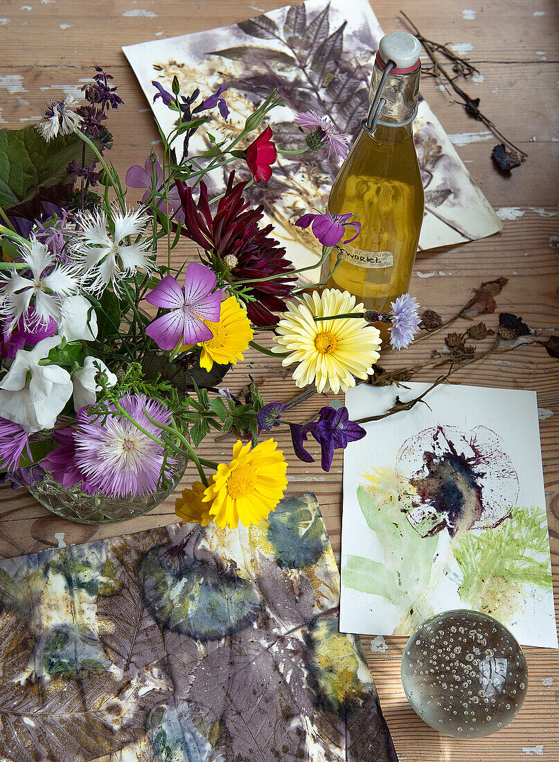 Wildblumenstrauß, Naturdrucke und Kräuteröl auf Holztisch