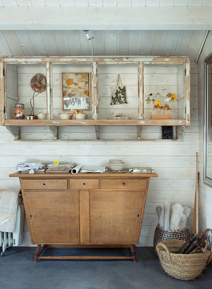 Wooden chest of drawers with vintage shelving and decoration in a bright country house room