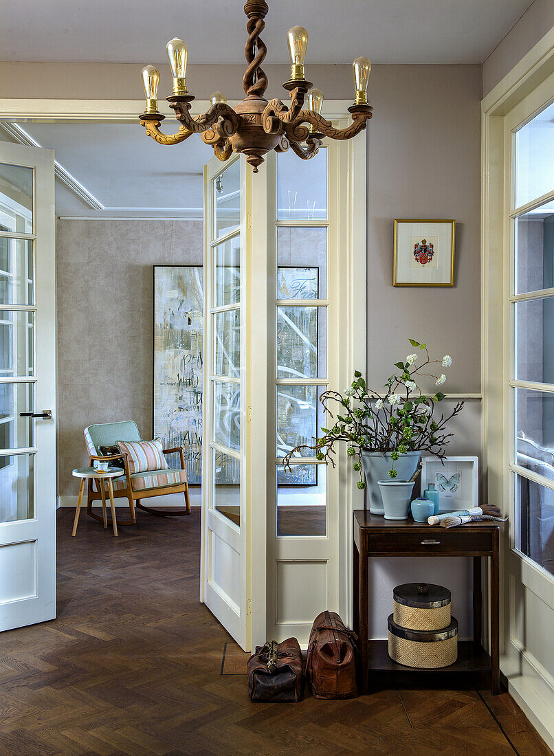 Entrance area with herringbone parquet flooring and antique chandelier, view into the living room