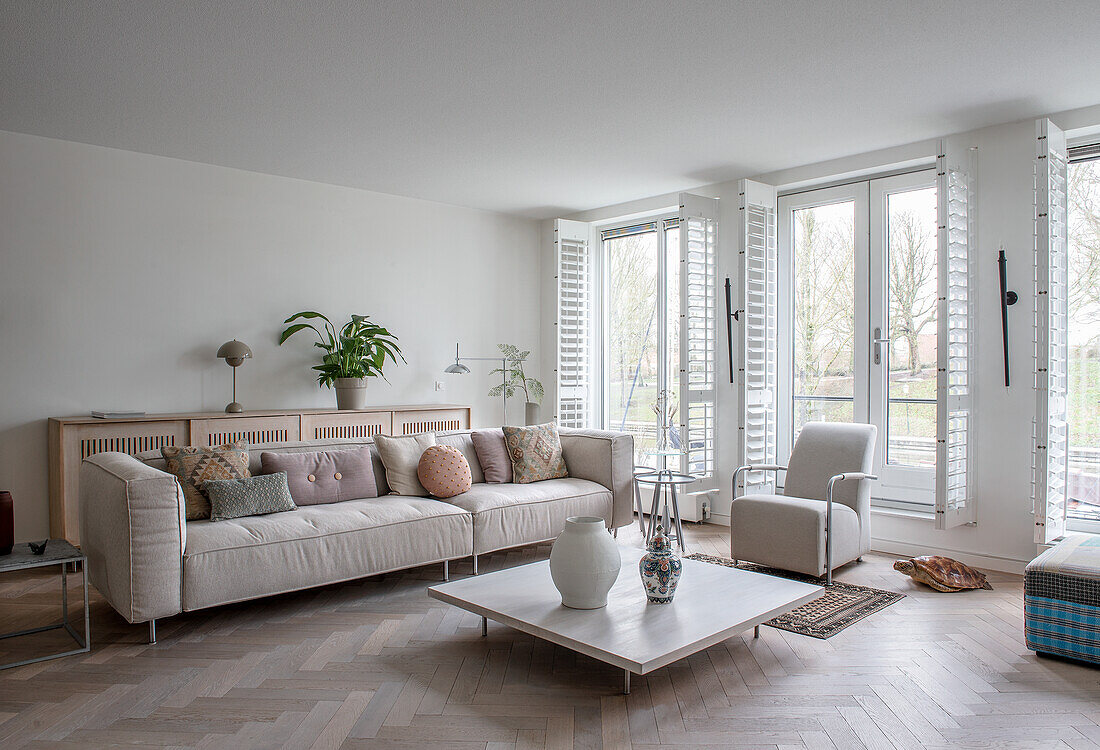 Bright living room with large windows, beige-coloured sofa and square coffee table