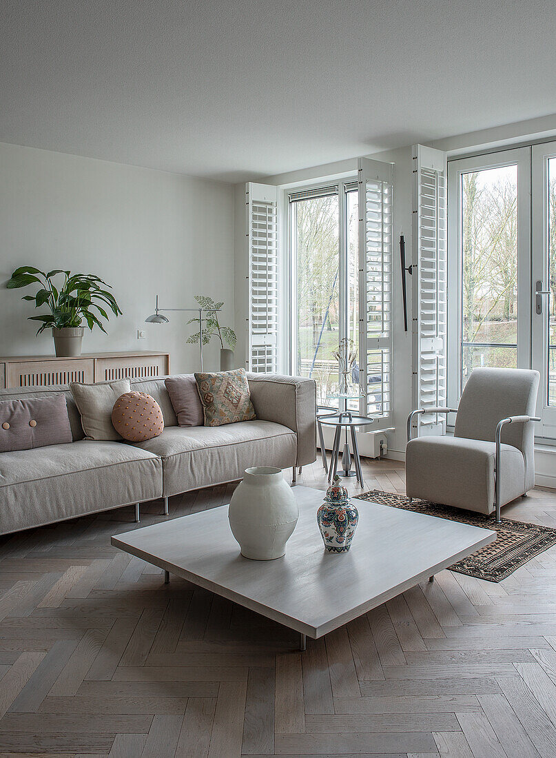 Monochrome living room with corner sofa, coffee table and herringbone parquet flooring