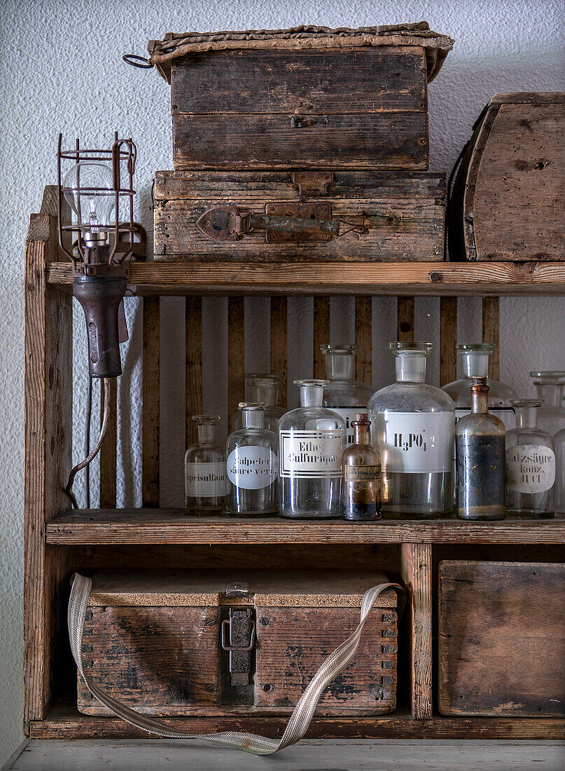 Old wooden shelf with vintage glass bottles and antique wooden boxes