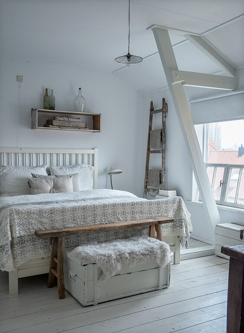 Country-style bedroom with lace bedspread, rustic wooden ladder and white wooden chest