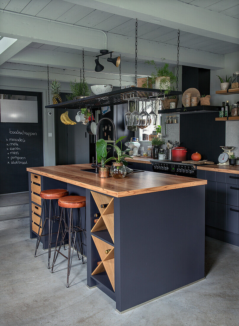 Modern kitchen with black island, wooden elements and chalkboard