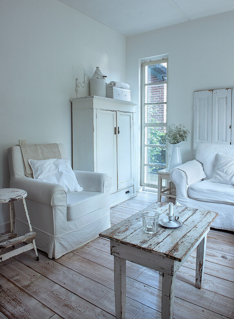 Living room in shabby chic style with white furniture and wooden floor