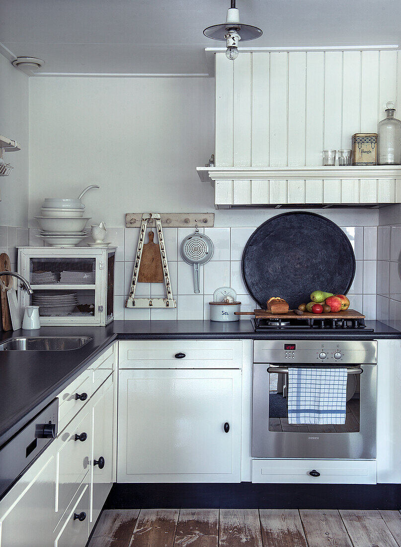 Country-style kitchen with white cabinets and black counters