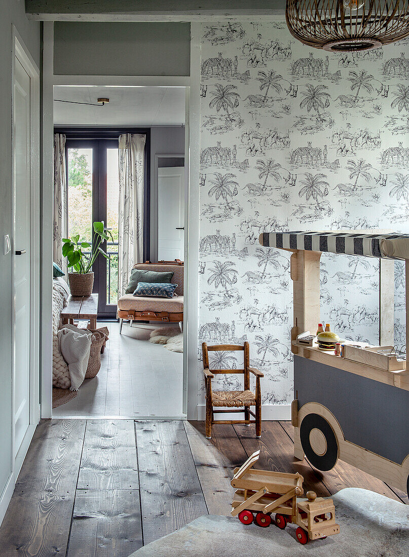 Playroom with wooden floor, wallpaper with safari motif and wooden toys