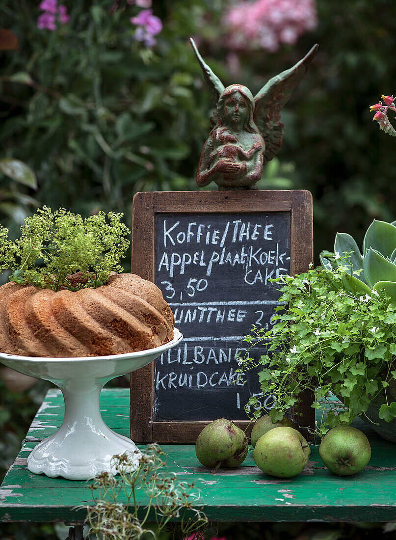 Garten-Café mit Kreidetafel, Gugelhupf und Dekoration aus grünen Pflanzen