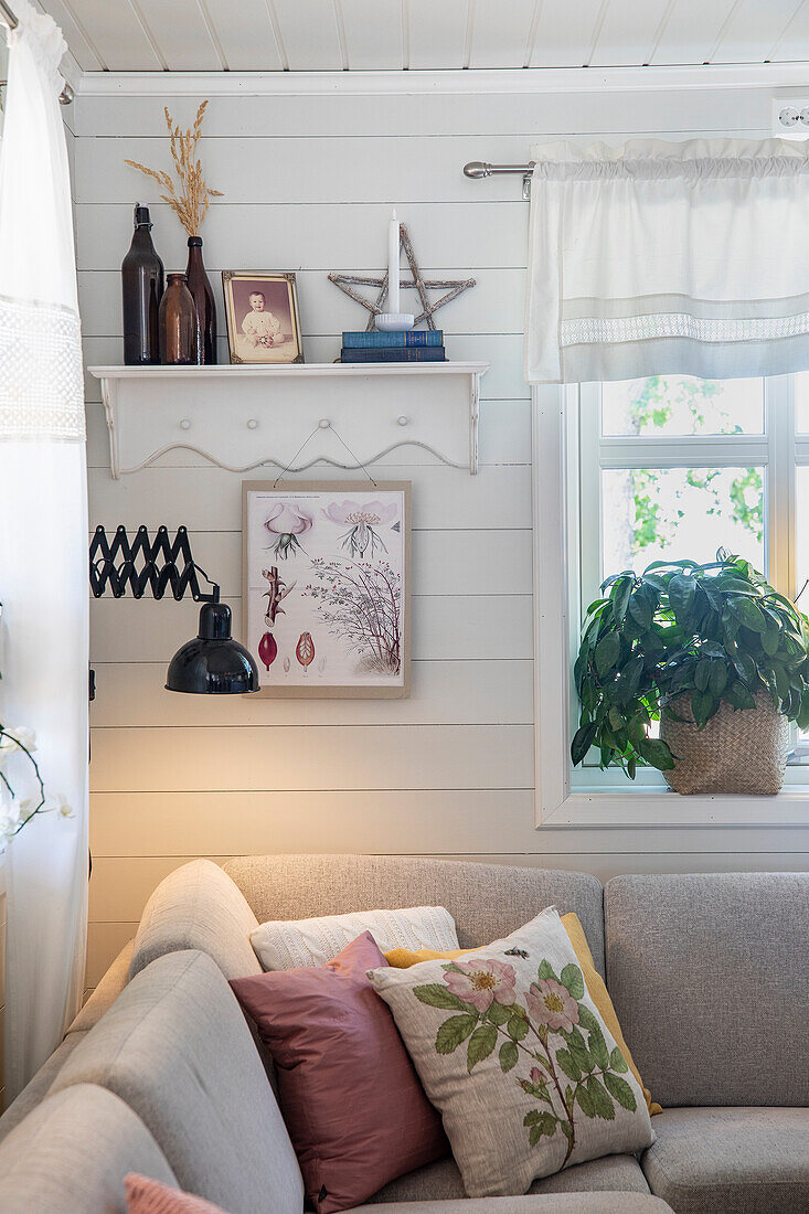 Living room with corner sofa, white wood panelling and floral accents