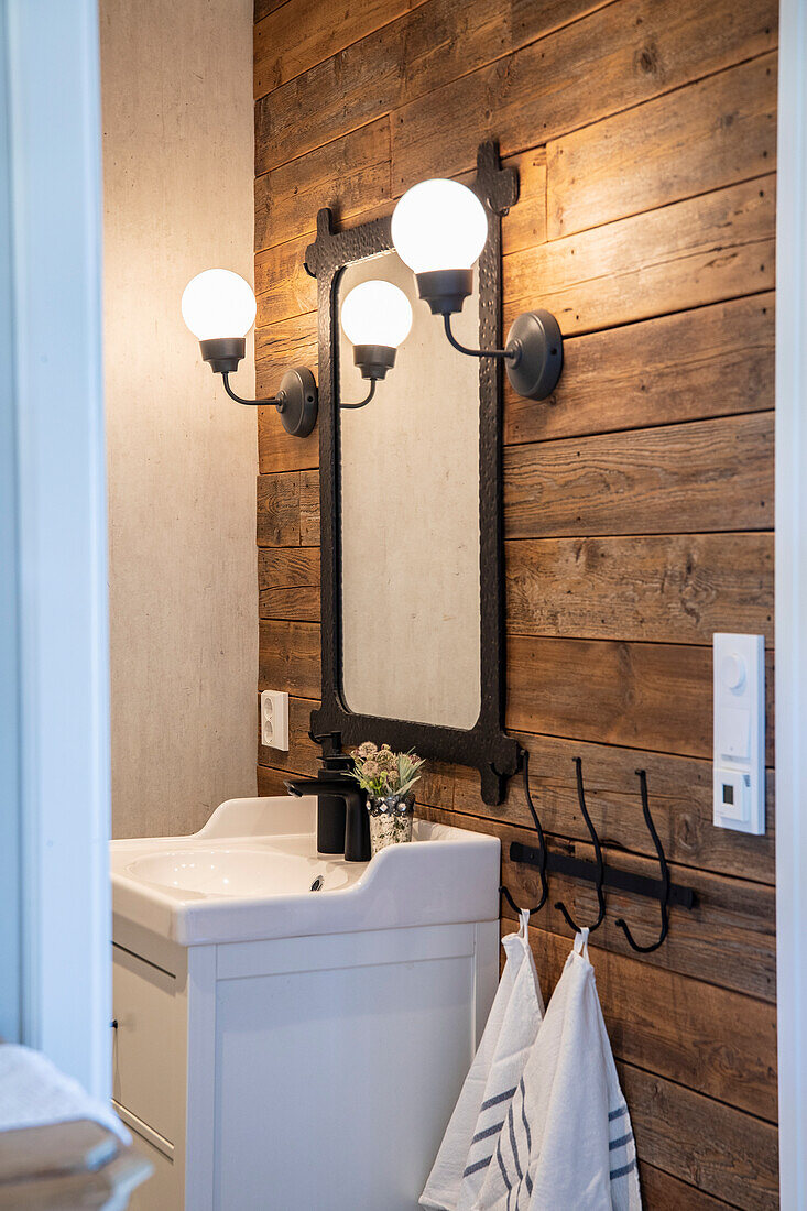 Small bathroom with wooden panelling, antique mirror and wall lamps