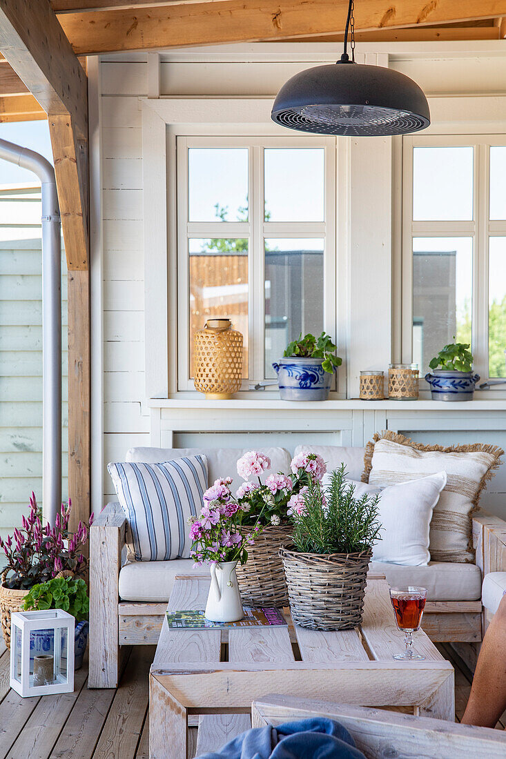 Covered terrace with wooden furniture, lanterns and flower pots