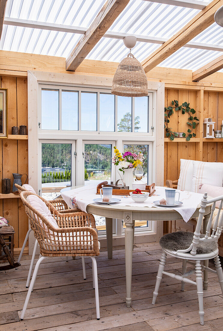 Conservatory with wooden walls, dining table and rattan chairs