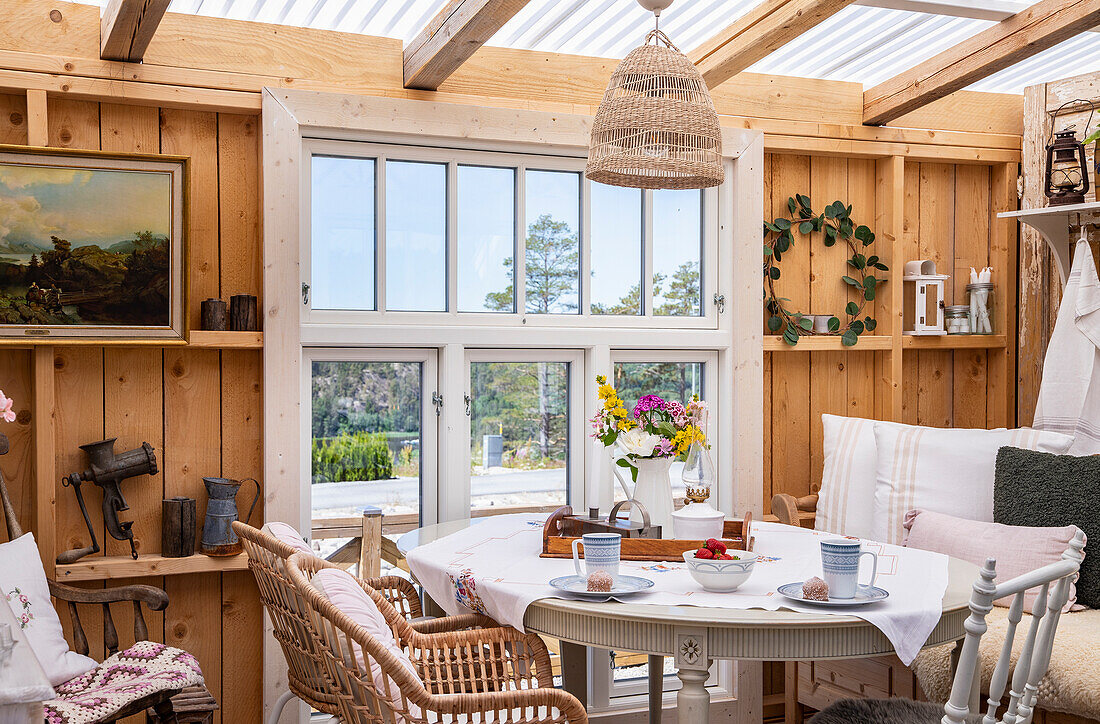 Dining area with rattan chairs in the light-flooded garden shed